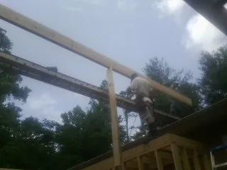 Carpenter setting a ridge beam over a new addition frame — Ice Dam Removal by Roofing Brothers in Holgate