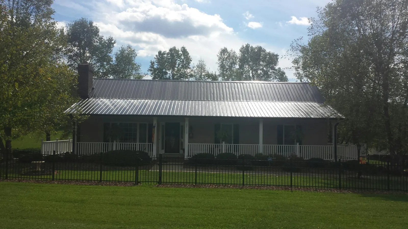 Gray metal roof on a brick ranch with a full width front porch — Gutter Guard Installation work by our crew in Holgate